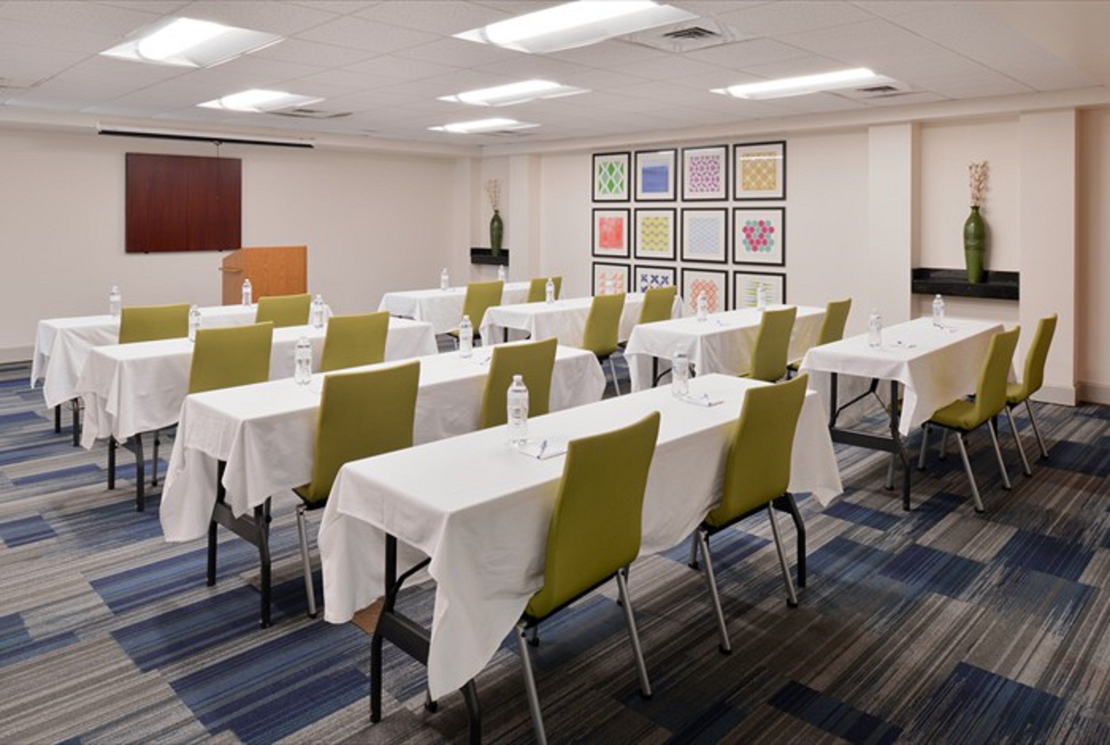 Un salón de conferencias con varias mesas y sillas dispuestas en filas.