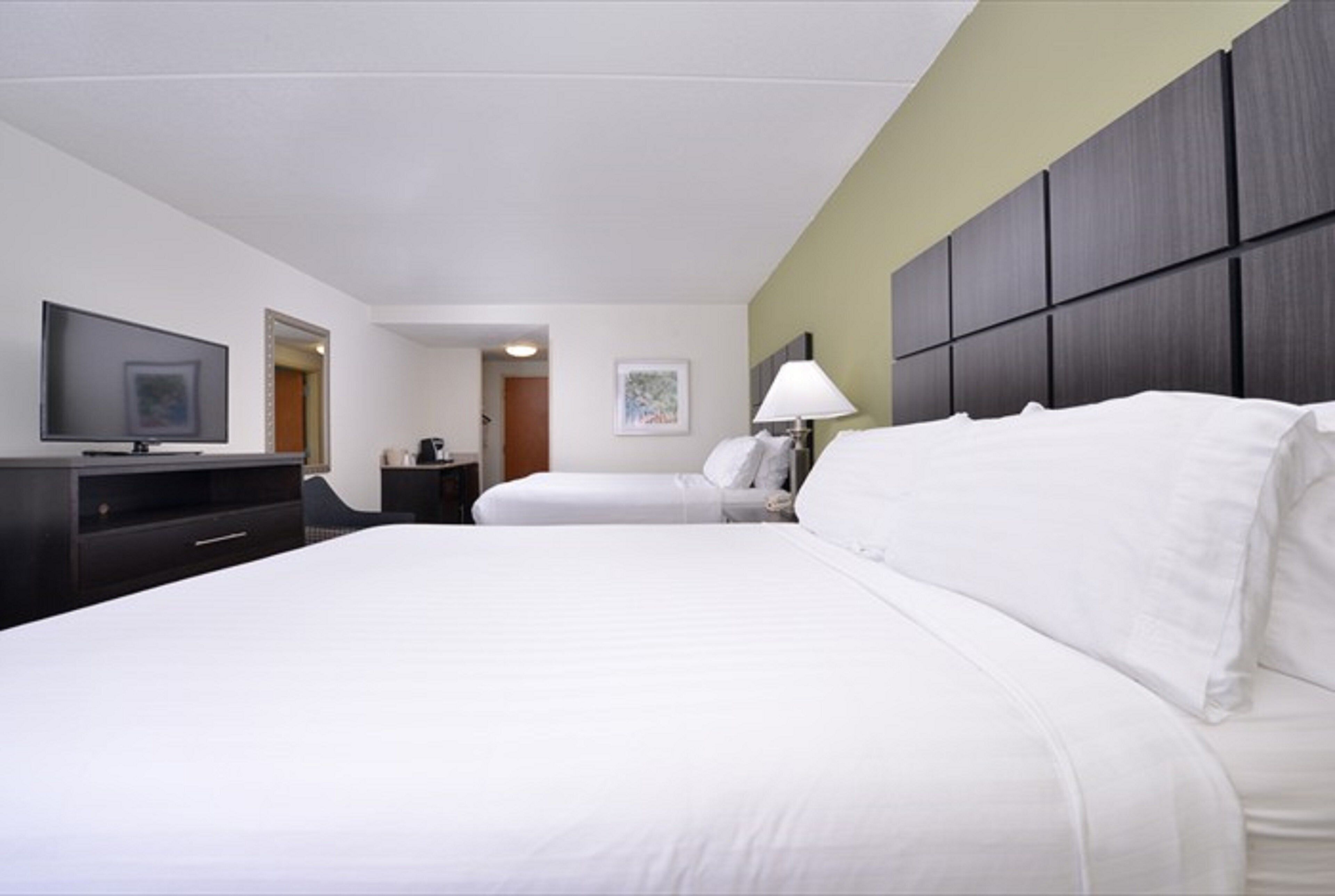 Una habitación de hotel con una cama, televisión, escritorio y lámpara.