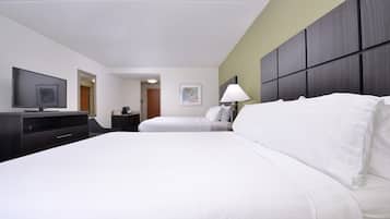 Una habitación de hotel con una cama, televisión, escritorio y lámpara.
