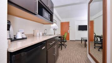 Habitación de hotel con kitchenette, comedor y televisor.