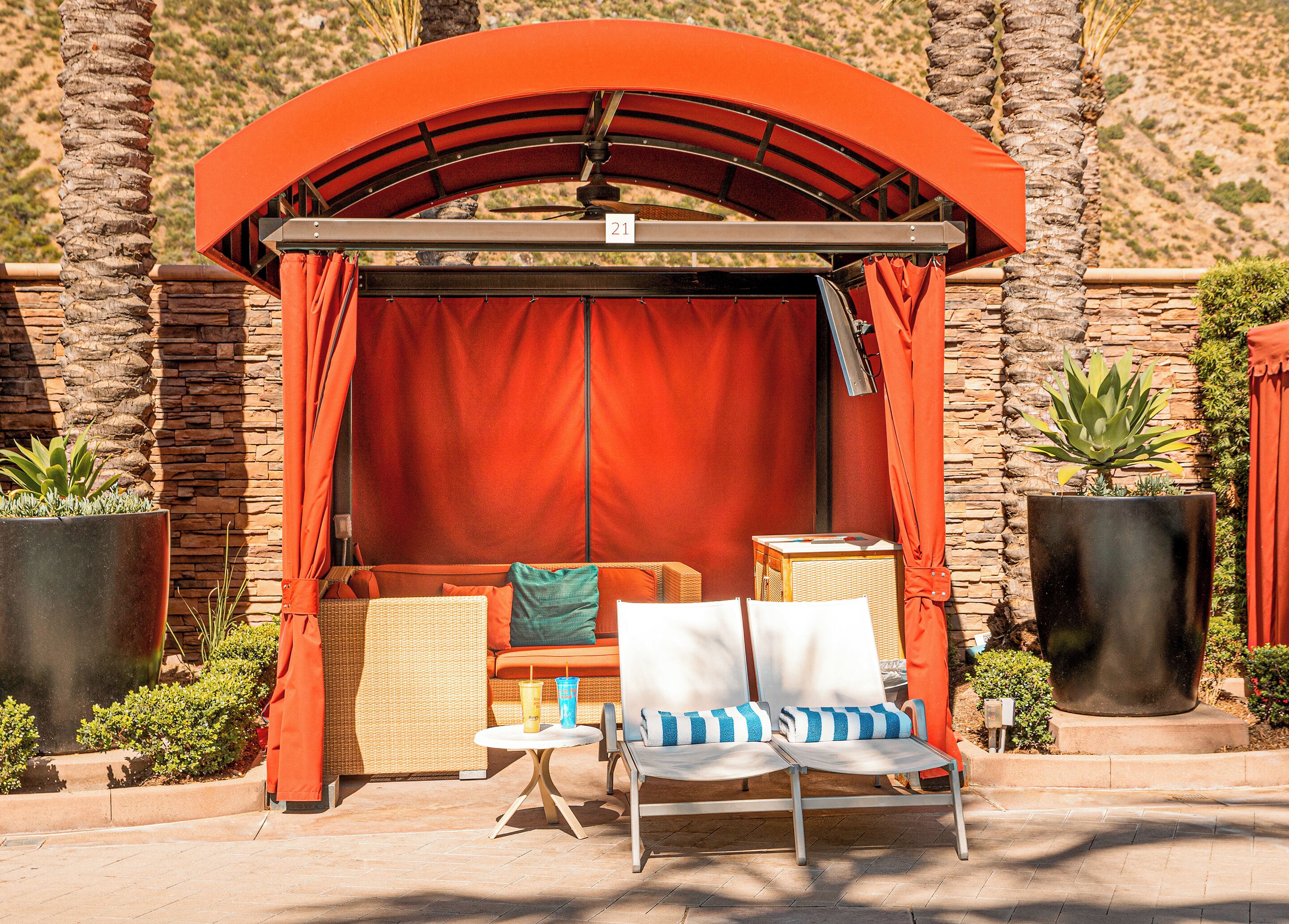 A covered seating area with wicker furniture, a small table, and potted plants.