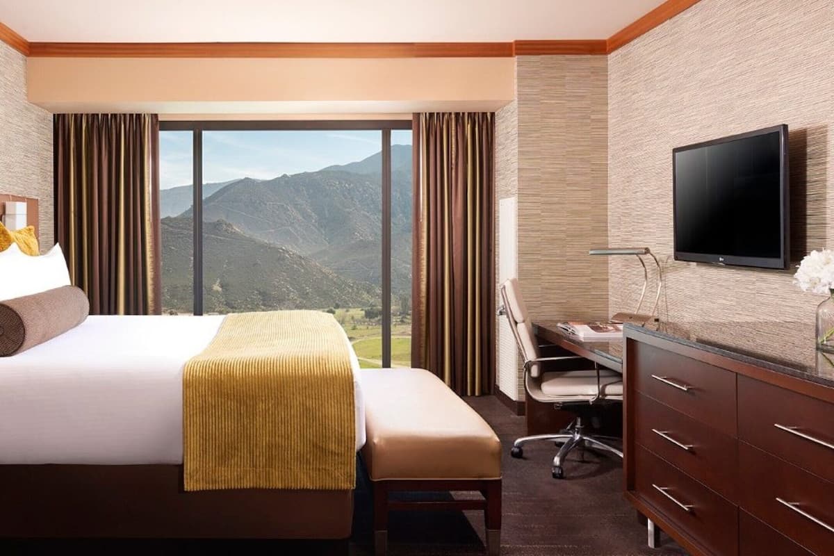 A hotel room with a large bed, a desk, and a TV.