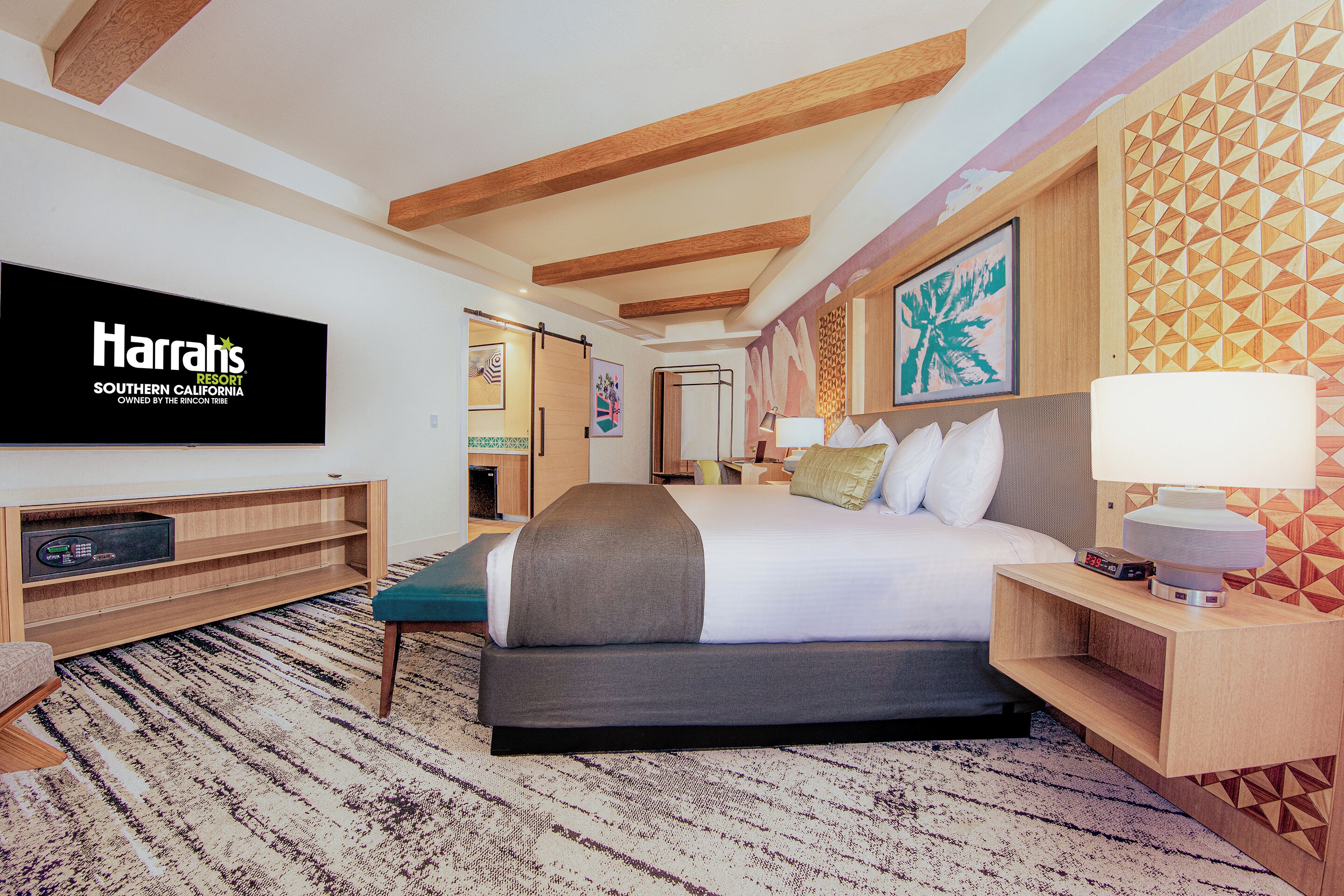 Una habitación de hotel con una cama, un televisor, un escritorio y una pared con diseños geométricos.