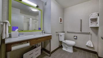 Een moderne badkamer met een grote spiegel, een wastafel, een toilet en een handdoekhouder.