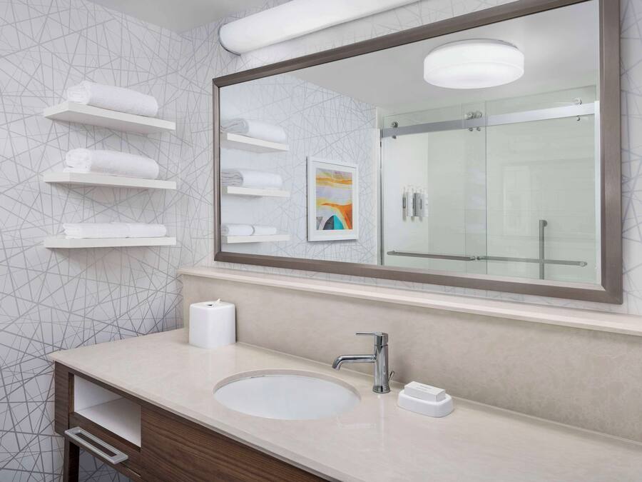 A modern bathroom with a large mirror, a round sink, and built-in towel racks.