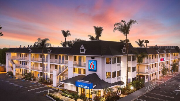 Un motel avec un panneau indiquant le chiffre « 6 », de nombreux balcons et un parking.