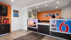 Un hall d’hôtel avec un comptoir d’accueil, une machine à café et un téléviseur fixé au mur.