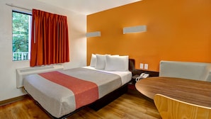 Une chambre d’hôtel avec un lit, une table et une fenêtre avec des rideaux.