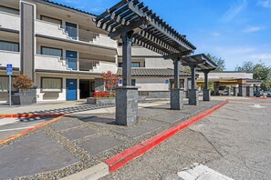 Un immeuble à plusieurs étages avec un espace de stationnement à l’avant.