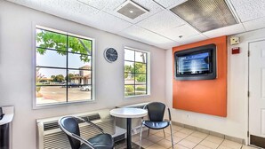 Une salle d’attente comprenant un comptoir d’accueil, deux chaises, une petite table et un téléviseur fixé au mur.