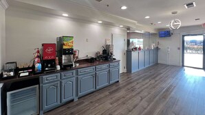 Et rummeligt køkkenområde med kaffestation, køleskab og mikrobølgeovn.