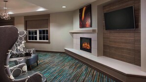 A modern living room with a fireplace, a flat-screen TV, and a patterned carpet. - Residence Inn by Marriott Detroit Novi (Novi)
