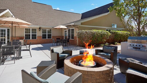 An outdoor patio with wicker furniture, a fire pit, and a grill. - Residence Inn by Marriott Detroit Novi (Novi)