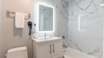 Un baño con inodoro, lavabo, espejo y ducha.