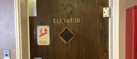 An elevator door with a sign indicating it is an elevator and a fire safety sign.