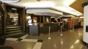 A hotel reception area with a check-in counter, a restaurant sign, and a reception desk. - Internacional Asuncion Dowtown (Asunción)