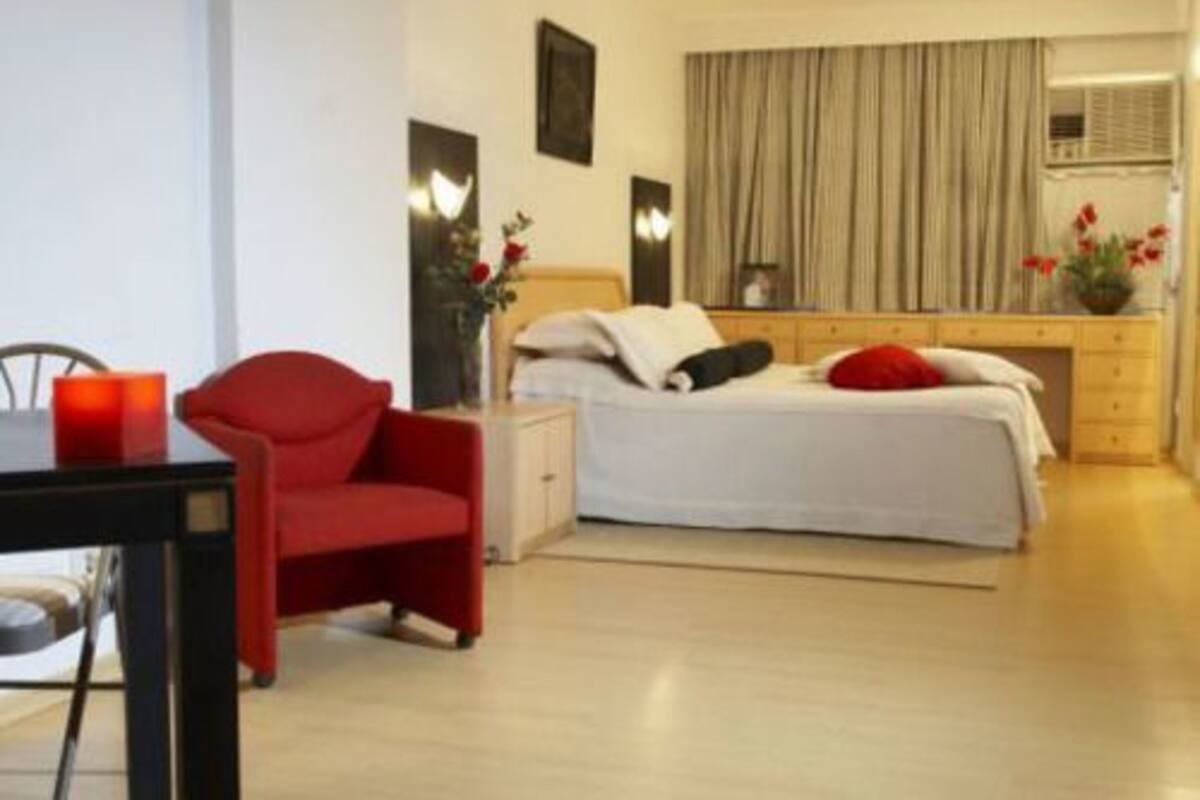 A modern hotel room with a bed, a desk, a chair, and a nightstand.