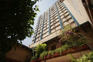 Balconies feature potted plants and flowering shrubs, adding a touch of greenery to the building's simple design.