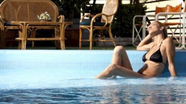 A pool area with a lounge chair and a table with chairs. - Internacional Asuncion Dowtown (Asunción)