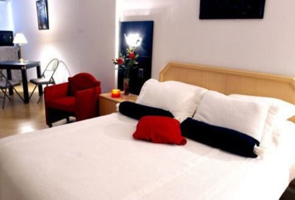 Relax in a cozy space with a made bed, a table, and a comfortable chair.