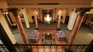 A lobby with a chandelier, two sofas, a coffee table, and a patterned rug. - Internacional Asuncion Dowtown (Asunción)