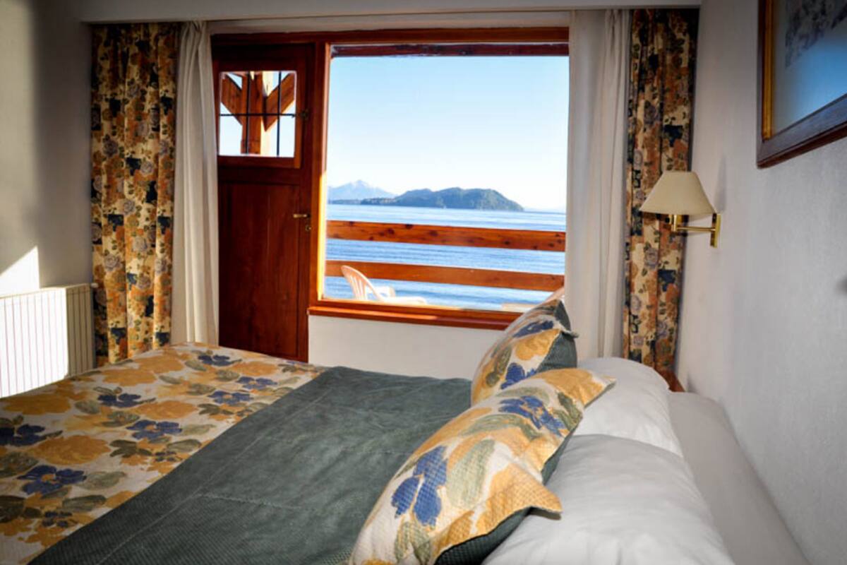 A bedroom with a bed, a window with a view of the sea, and curtains.
