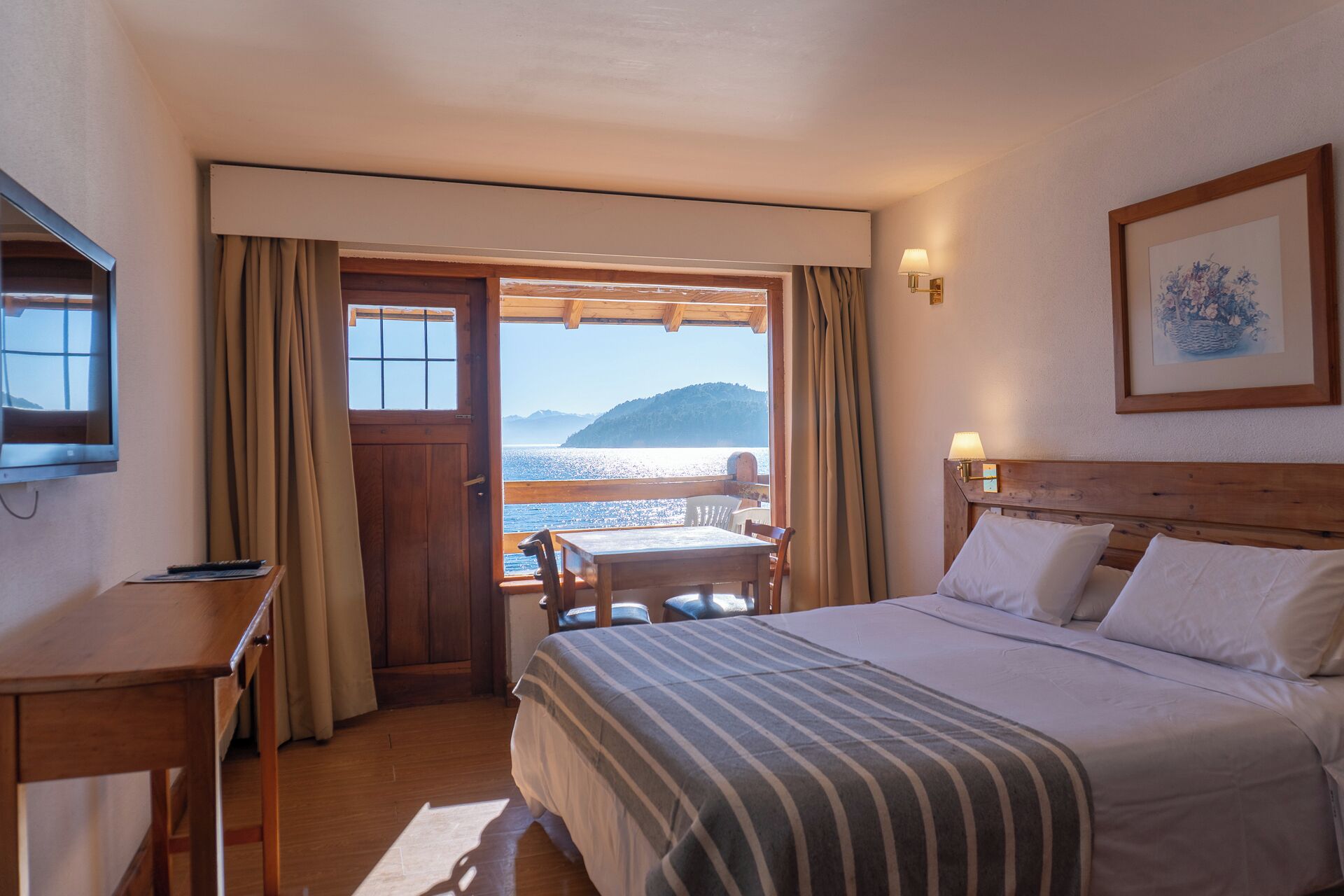 Habitación de hotel con cama, escritorio, silla y vista al mar.