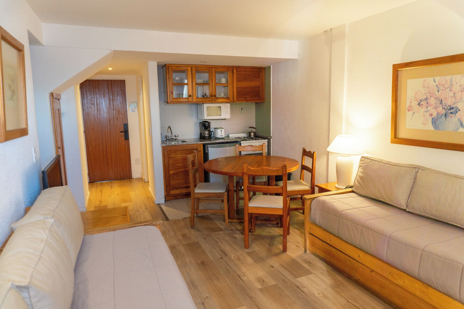 Een ruimtelijke woonruimte met kitchenette, een eethoek en een bank.