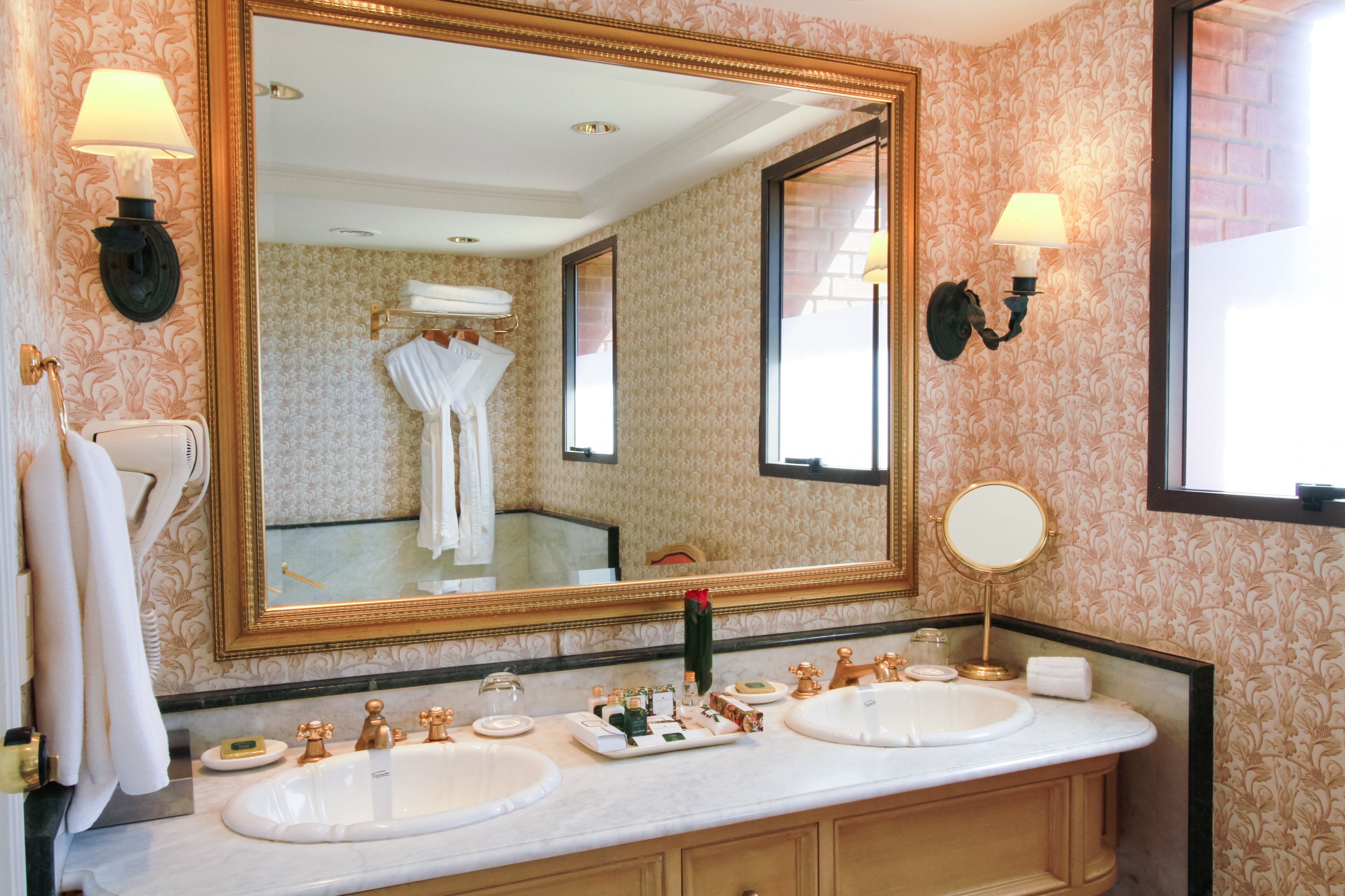 A bathroom with two sinks, a large mirror, and wall sconces.