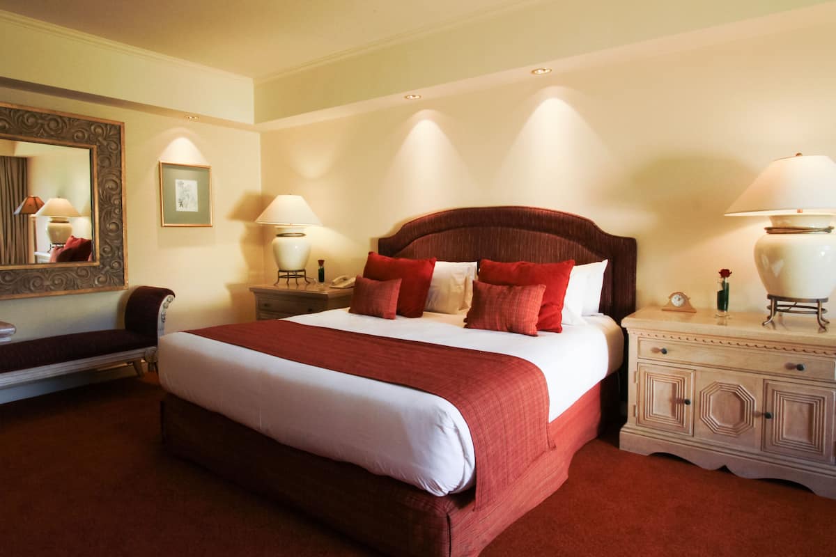 Une chambre d’hôtel avec un grand lit, deux tables de chevet, un miroir et une commode.