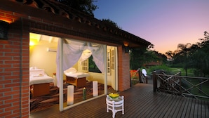 A private suite with a balcony, a bed, a small table, and a glass enclosure with a view of the garden. - Iguazu Grand Resort Spa & Casino (Puerto Iguazú)