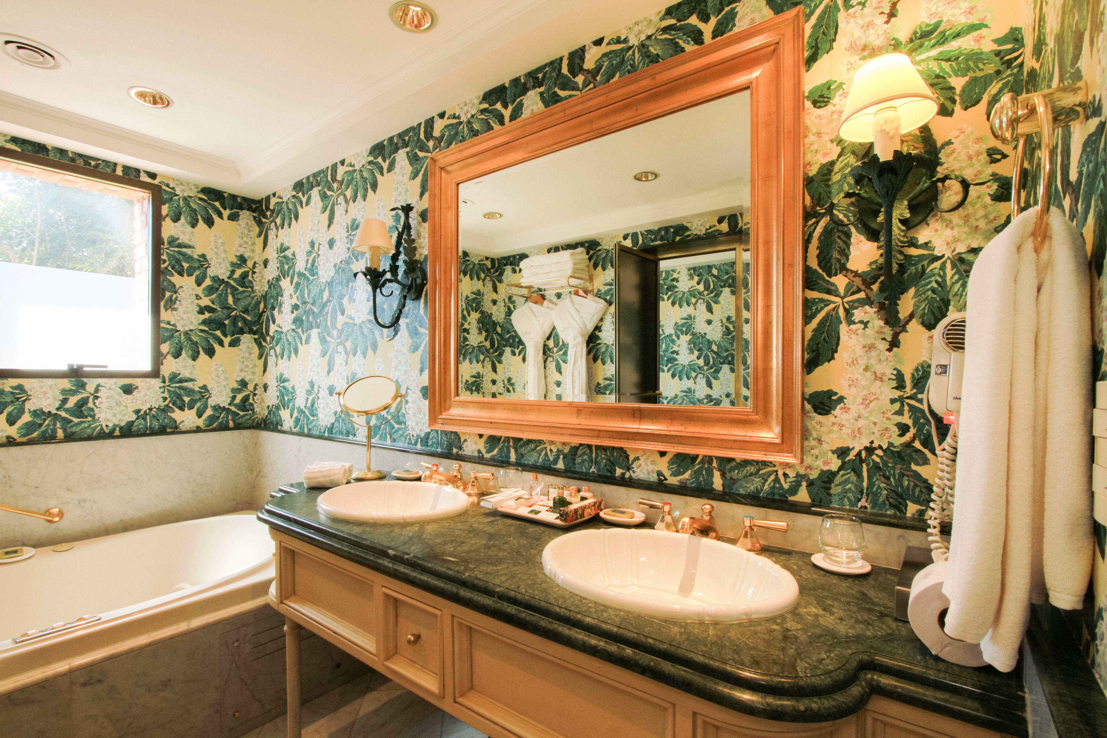 A bathroom with two sinks, a large mirror, and a bathtub.