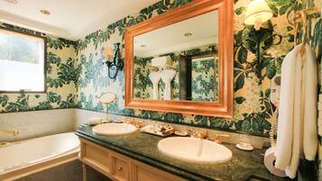 A bathroom with two sinks, a large mirror, and a bathtub.