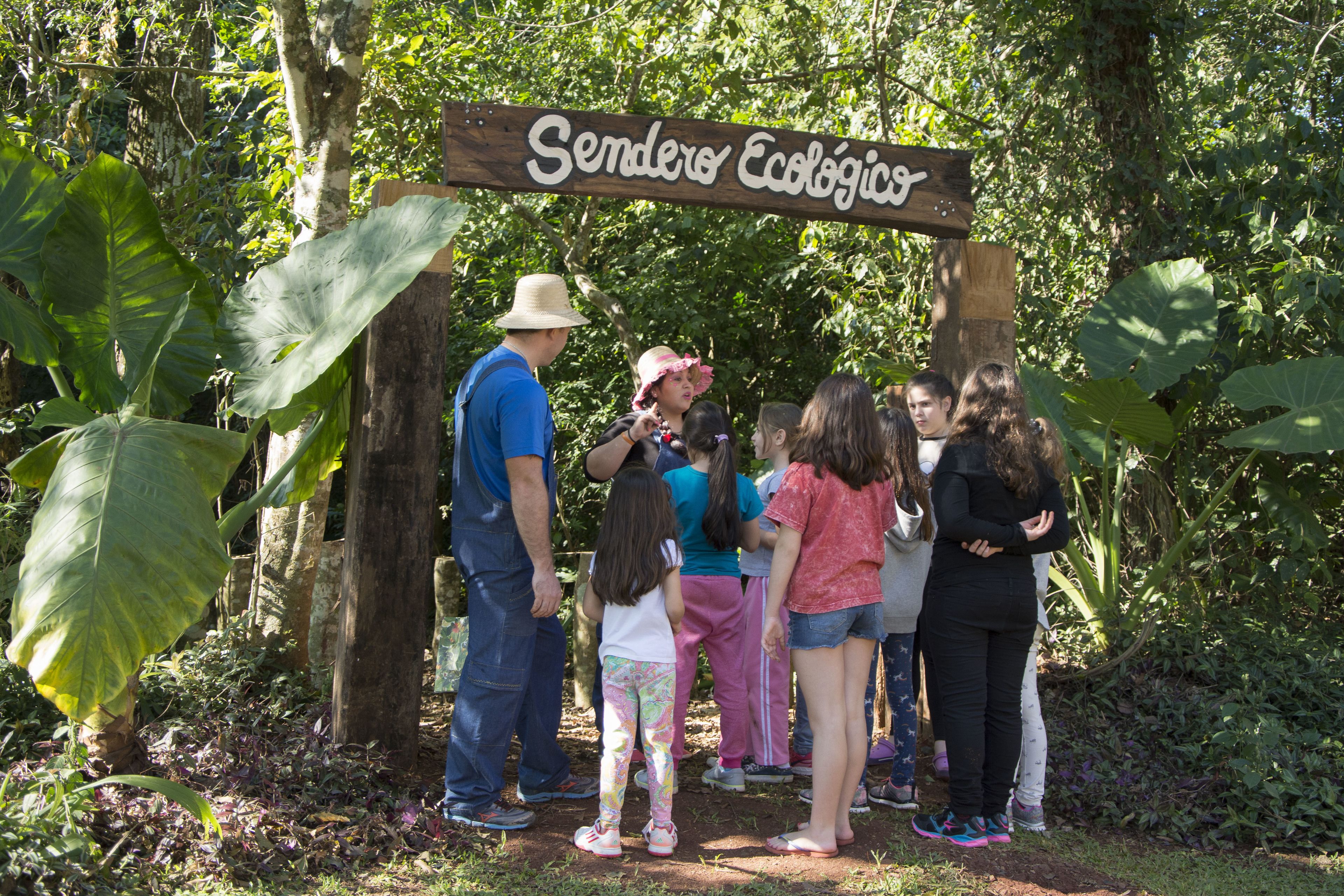 Un grupo de personas de pie bajo un letrero de madera que dice "Sendero Ecológico".