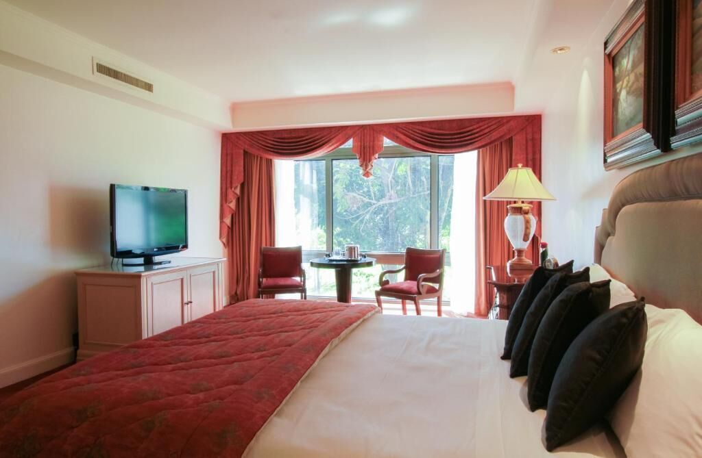 Una habitación de hotel con cama, televisión, escritorio con lámpara y una silla.
