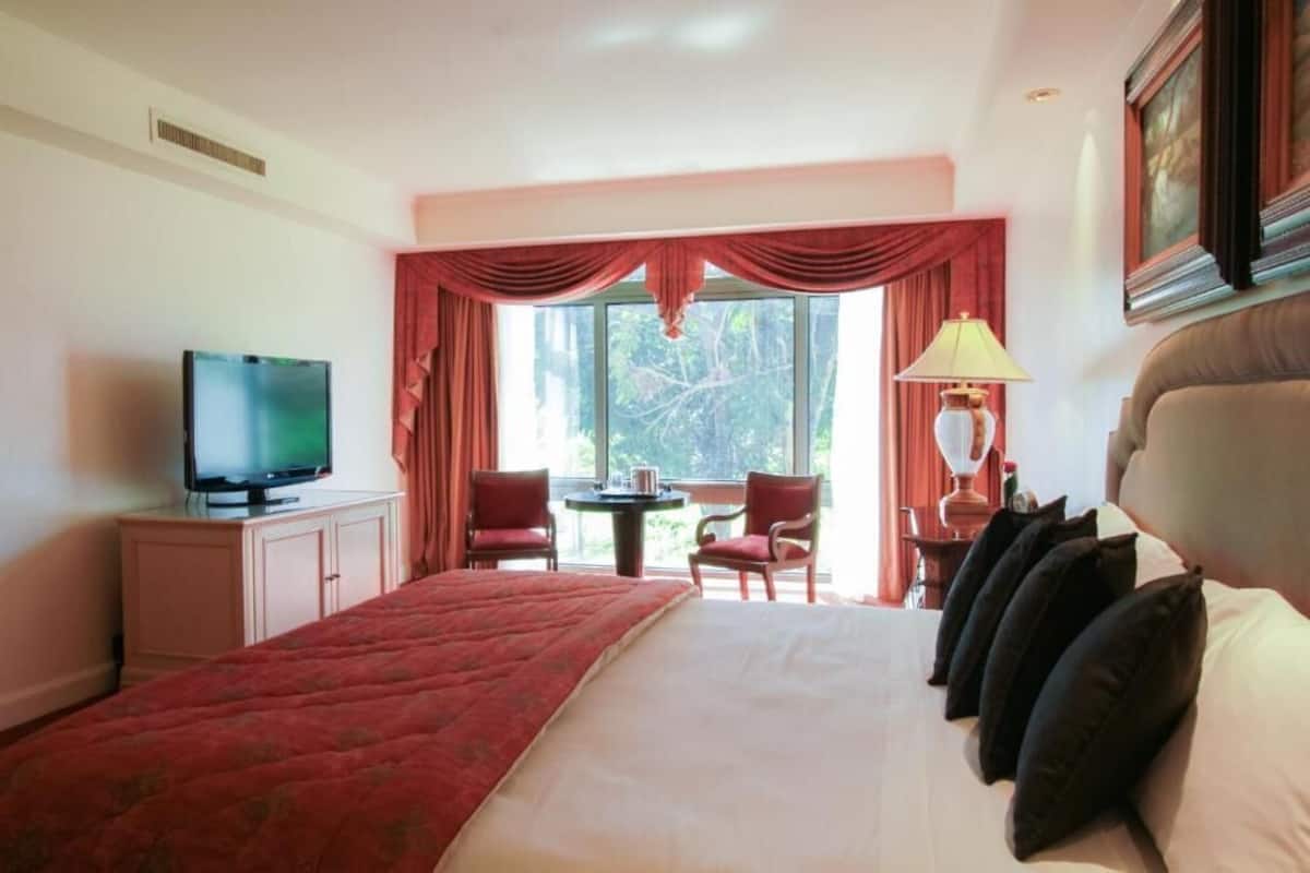 Une chambre d’hôtel avec un lit, une télévision, un bureau avec une lampe et une chaise.
