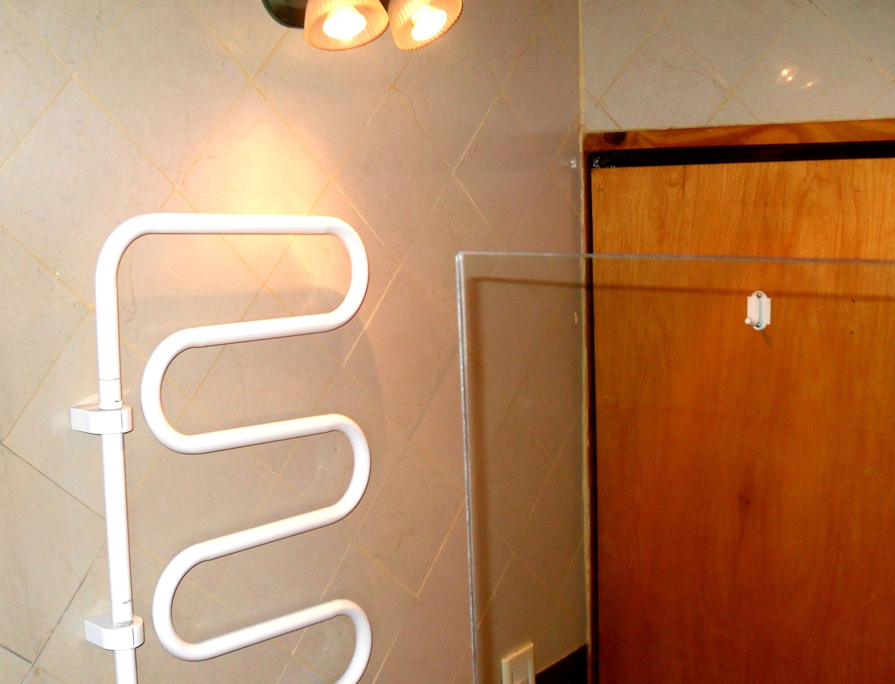 Um banheiro com um porta-toalhas branco, uma porta de madeira e piso ladrilhado.