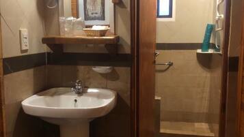 A bathroom with a sink, mirror, and shower area.