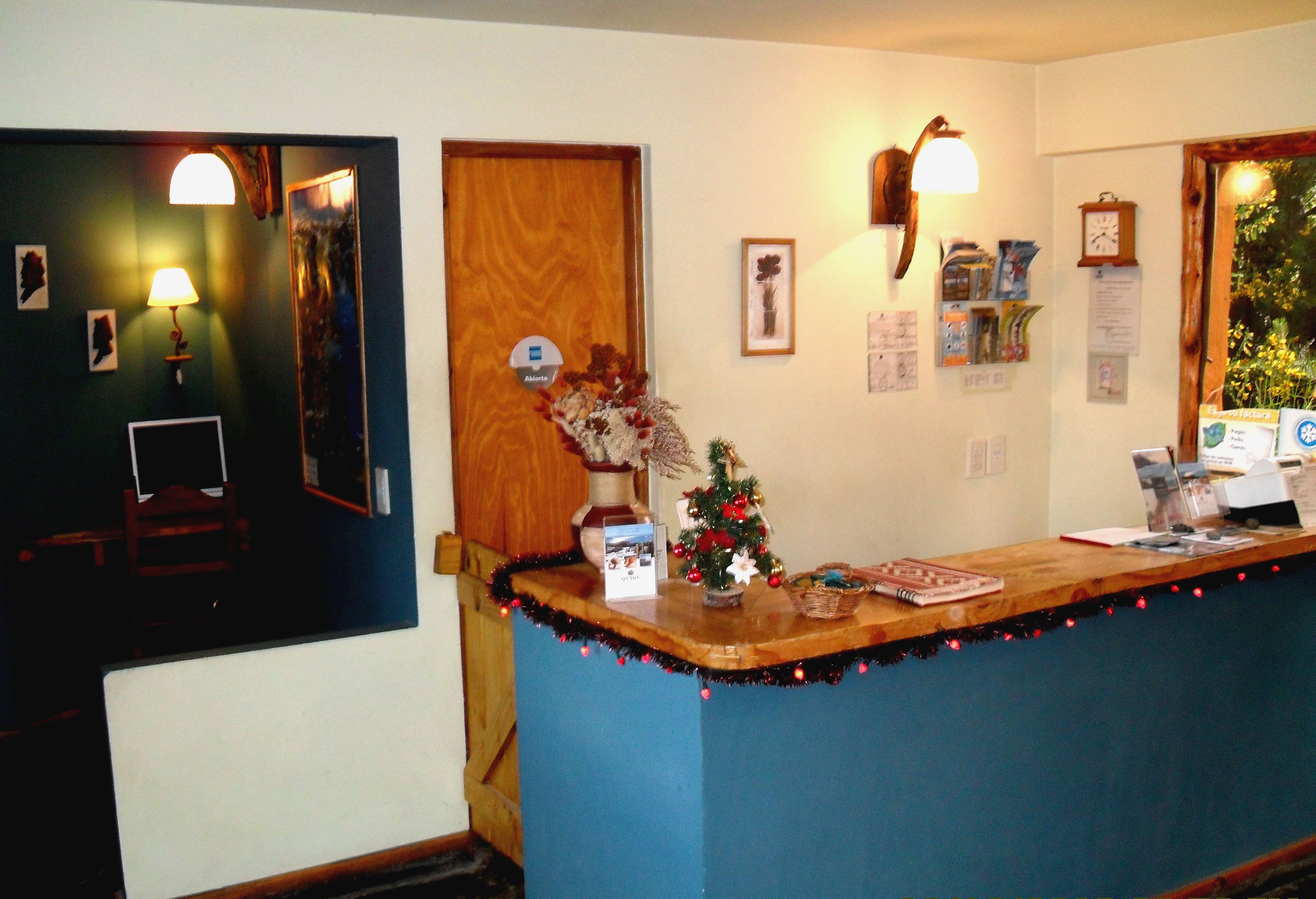 A reception desk with a Christmas tree, framed pictures, and a clock on the wall.