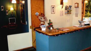 A reception desk with a Christmas tree, framed pictures, and a clock on the wall.