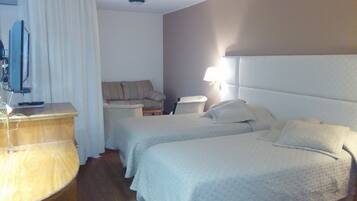 Habitación de hotel con dos camas, un escritorio con computadora, un sofá y una lámpara.