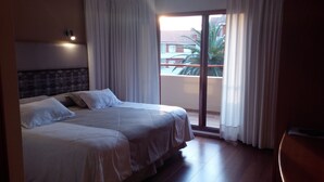 A hotel room with two beds, a headboard, a nightstand, a window with curtains, and a view of the outside balcony. - Hotel Remanso (Punta del Este)