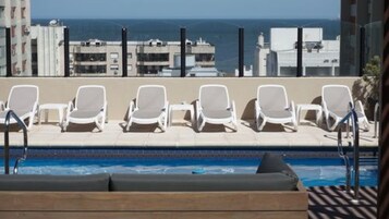 Una piscina al aire libre, sombrillas, sillones reclinables de piscina