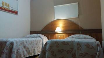 Quarto com duas camas, cabeceira de madeira, luminária e um cartaz na parede.