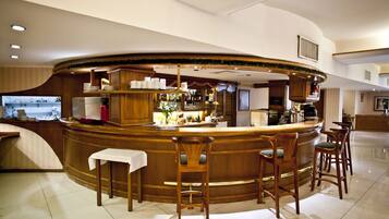 A bar area with a curved counter, bar stools, and a small table.