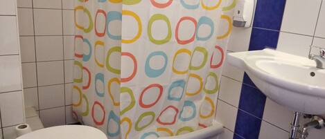 A bathroom with a toilet, a sink, and a shower curtain with a colorful circular pattern.