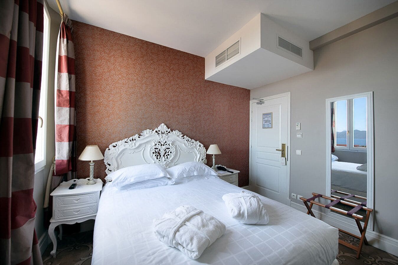 Habitación de hotel con una cama grande, dos mesitas de noche, un armario y una ventana con vistas.