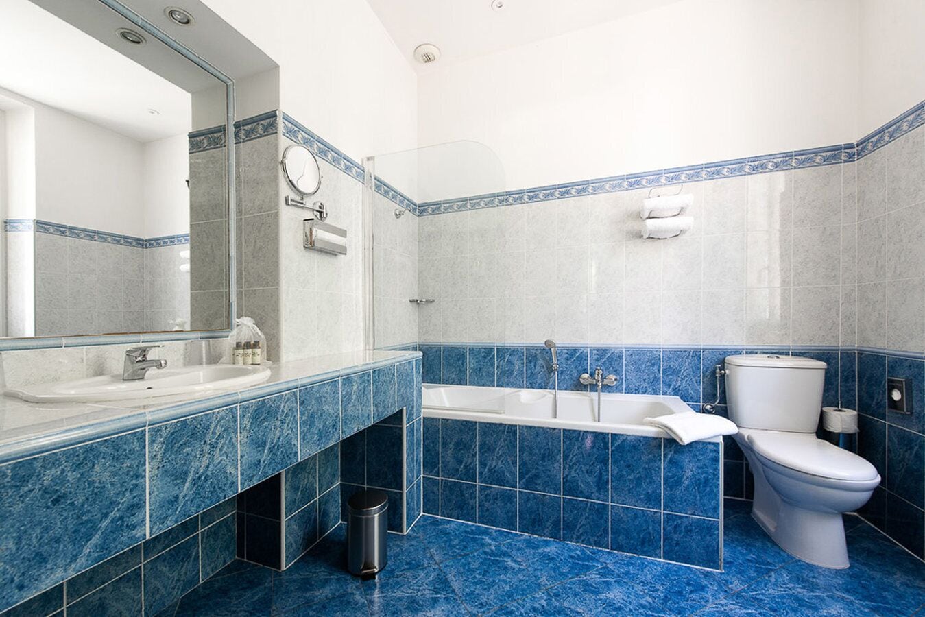 A bathroom with a large mirror, a sink, a bathtub, and a toilet.