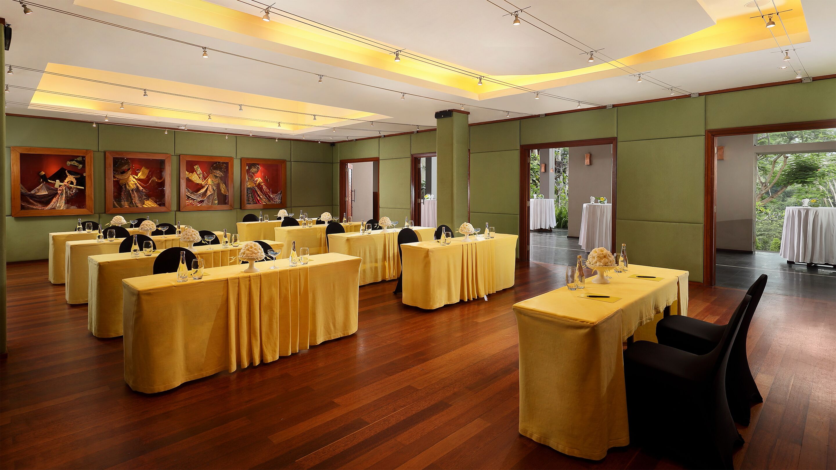 Un salón de banquetes con varias mesas dispuestas para comer, que presenta un suelo de madera y paredes verdes.