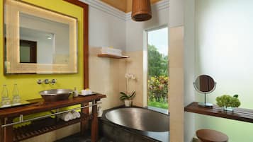 Un baño moderno con un espejo grande, una bañera y un ventanal con vistas a zonas verdes.